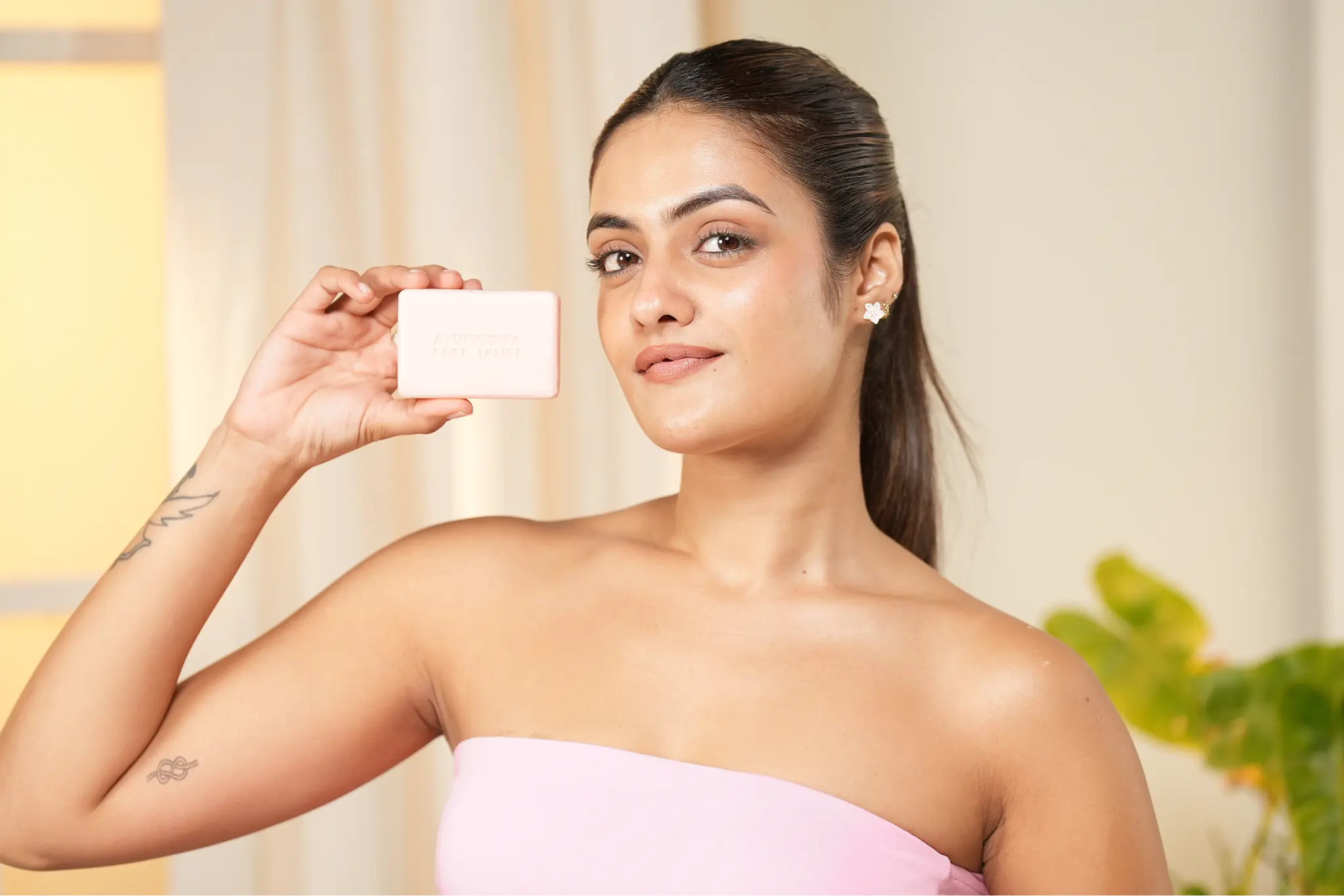 Woman holding a white square in front of her face with a blurred background